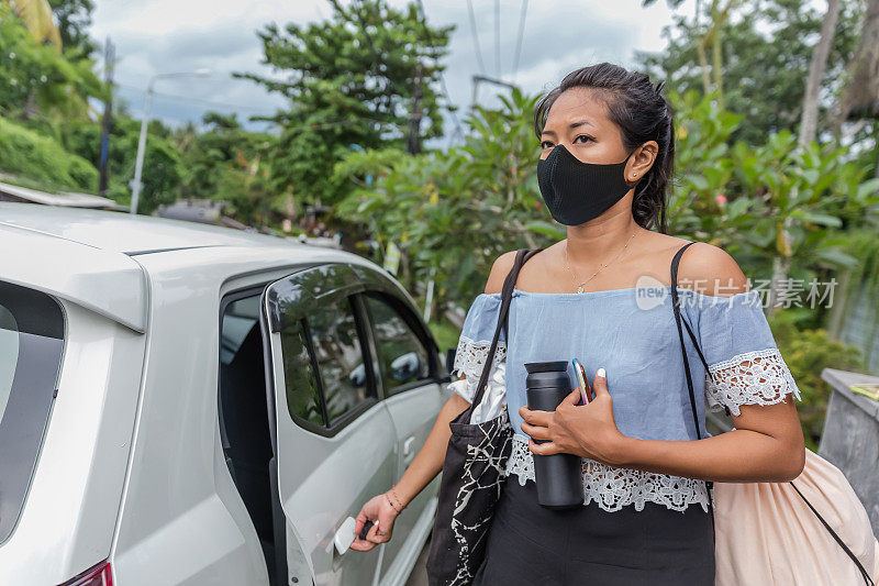 一名东南亚妇女在Covid - 19大流行期间打开车门